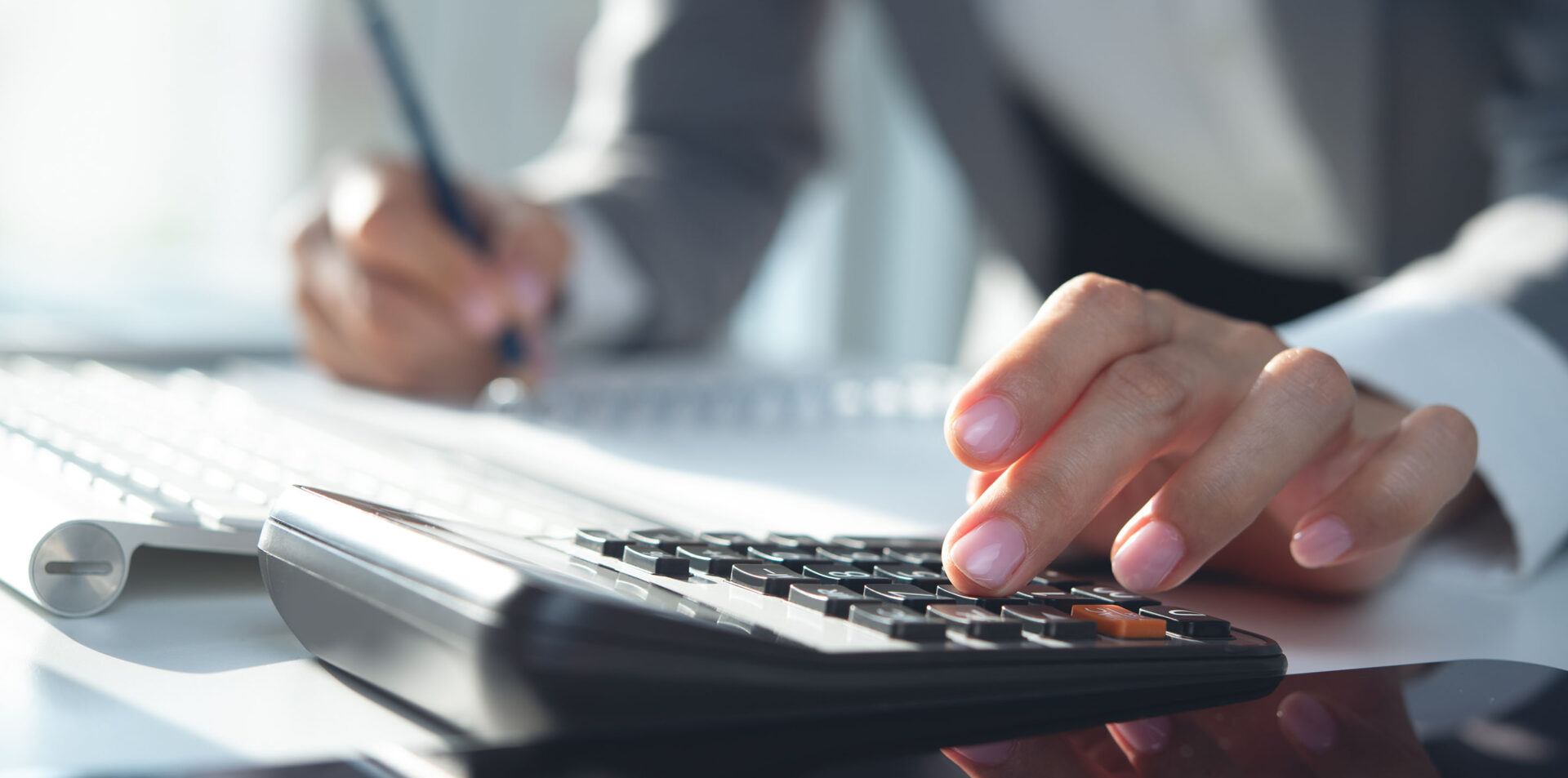 Close up, business woman working at office, using calculator to calculate company finance, accounting with laptop computer on table, budget management. Doing finance, budgeting and tax calculation